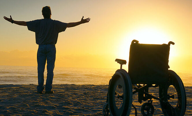 worshipping man standing next to empty wheelchair