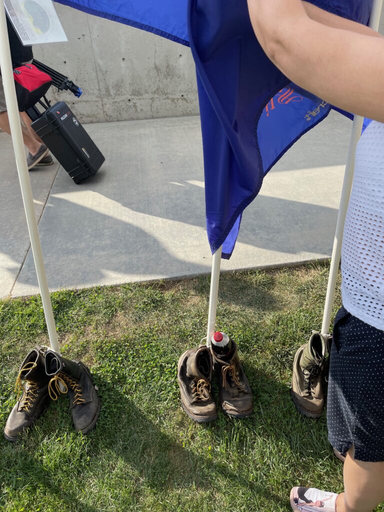 The boots below the flag for Andrew Ashcraft, one of the Granite Mountain Hotshots. Note the bottle of Dr. Pepper placed there by his mother.