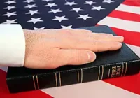 photo of hand on Bible placed on an American flag