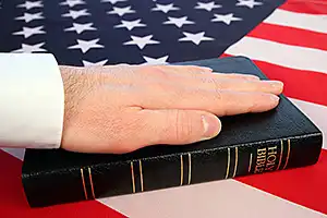 photo of hand on Bible placed on an American flag